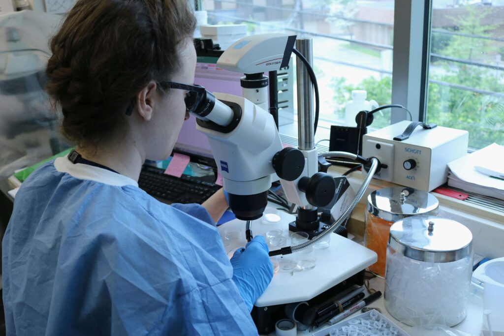 Surgical resident conducting research using a microscope for ACS Resident Research Scholarships 2026