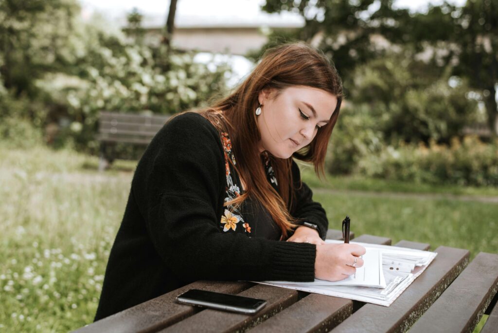 Student writing a scholarship essay on a laptop at a study desk with papers and notes, focused on creating a standout application.